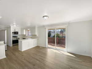 Kitchen featuring light wood-style floors, appliances with stainless steel finishes, ornamental molding, and light countertops