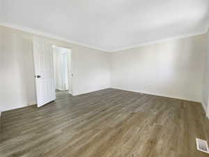 Unfurnished room featuring visible vents, baseboards, wood finished floors, and crown molding