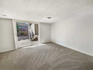 Carpeted spare room with visible vents, baseboards, and a textured ceiling