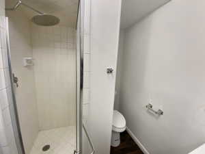 Full bath with a shower stall, toilet, and baseboards