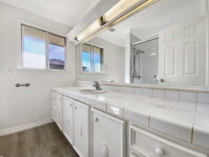 Bathroom with vanity, wood finished floors, visible vents, baseboards, and an enclosed shower