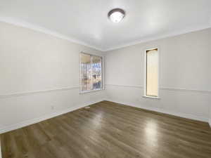 Spare room featuring ornamental molding, wood finished floors, visible vents, and baseboards