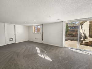 Below grade area featuring baseboards, carpet, and a textured ceiling