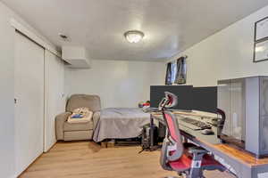 Bedroom featuring a closet, visible vents, a textured ceiling, and light wood-type flooring