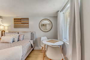 Bedroom featuring light wood-type flooring, baseboards, and a textured ceiling