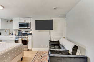 Interior space featuring a sink, light wood-type flooring, appliances with stainless steel finishes, and white cabinetry