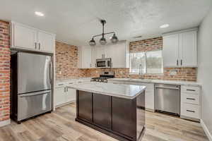 Kitchen with visible vents, light wood-style flooring, a sink, appliances with stainless steel finishes, and white cabinetry