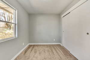 Unfurnished bedroom with carpet flooring, multiple windows, baseboards, and a closet