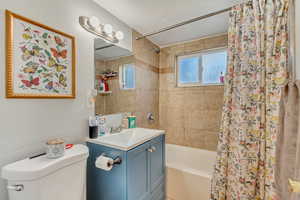 Bathroom with vanity, toilet, and shower / bath combo with shower curtain