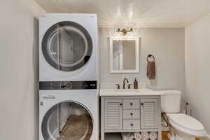 Bathroom featuring vanity, stacked washer / dryer, and toilet