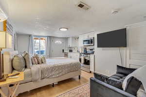 Bedroom featuring visible vents, a textured ceiling, light wood-type flooring, and a sink