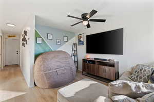 Living room featuring baseboards, light wood-type flooring, and ceiling fan