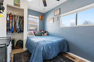 Bedroom with ceiling fan, visible vents, baseboards, and wood finished floors