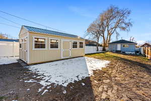 Rear view of property with metal roof, an outbuilding, and a fenced backyard