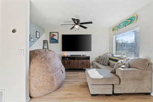 Living area featuring a textured ceiling, light wood-type flooring, and a ceiling fan