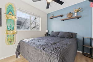 Bedroom with a textured ceiling, wood finished floors, baseboards, and ceiling fan