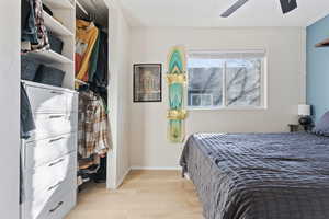 Bedroom featuring baseboards, a textured ceiling, light wood-style floors, and a ceiling fan