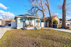 View of front facade with driveway, a shingled roof, a front lawn, and fence