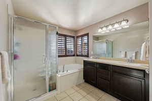 Bathroom featuring tile patterned floors, a bath, a stall shower, and a sink