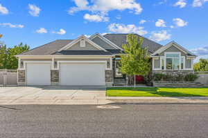 Craftsman inspired home with a front lawn, driveway, stone siding, fence, and a garage