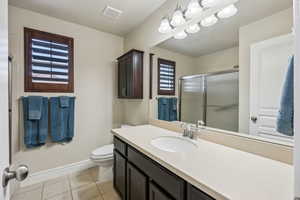 Bathroom featuring baseboards, visible vents, a shower stall, tile patterned floors, and toilet