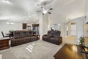 Living area with baseboards, high vaulted ceiling, light tile patterned flooring, arched walkways, and light carpet