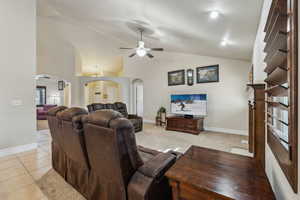 Living room featuring light tile patterned floors, a ceiling fan, arched walkways, and baseboards