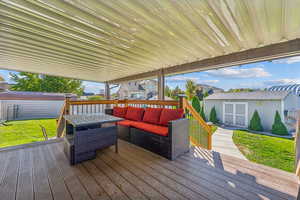 Deck featuring a storage shed, an outbuilding, a yard, and an outdoor living space