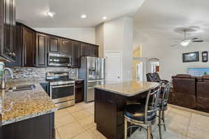 Kitchen with a sink, arched walkways, appliances with stainless steel finishes, and open floor plan