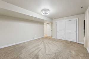 Unfurnished bedroom with visible vents, carpet, baseboards, and a textured ceiling