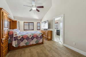 Bedroom with baseboards, ceiling fan, high vaulted ceiling, light carpet, and ensuite bath