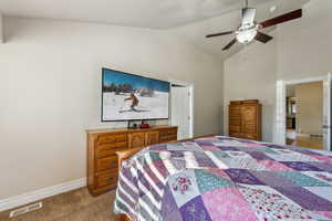 Bedroom with high vaulted ceiling, light colored carpet, visible vents, and baseboards