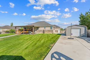 View of front of house with fence, a front yard, an outbuilding, a storage unit, and a gate