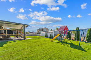 View of yard with an outbuilding, fence, a playground, a storage shed, and a wooden deck