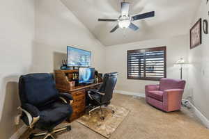 Carpeted home office with baseboards, ceiling fan, and vaulted ceiling