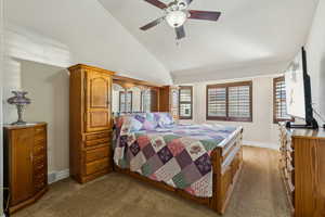 Bedroom with visible vents, a ceiling fan, carpet floors, baseboards, and vaulted ceiling