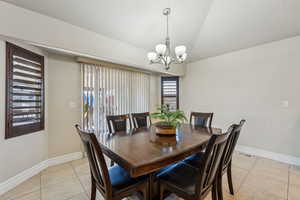 Dining area with visible vents, lofted ceiling, an inviting chandelier, light tile patterned floors, and baseboards