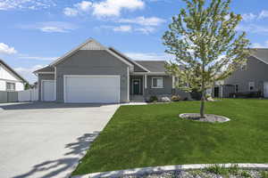 View of front facade with a garage, concrete driveway, a storage shed, and a shingled roof