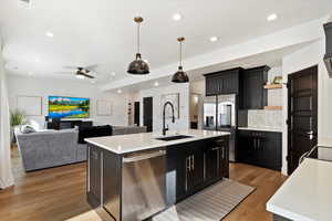 Kitchen featuring open shelves, appliances with stainless steel finishes, light countertops, and a sink