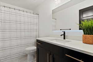 Bathroom featuring toilet, marble finish floor, and vanity