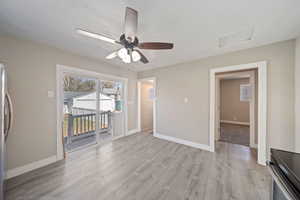 Empty room featuring light wood-style flooring, attic access, baseboards, and a ceiling fan