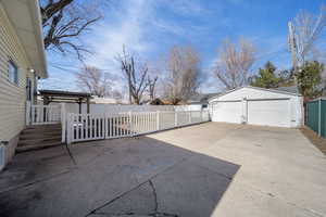 View of patio / terrace featuring a garage, an outdoor structure, and fence