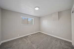 Spare room featuring visible vents, baseboards, and carpet