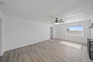 Unfurnished living room with baseboards, light wood-style floors, and a ceiling fan