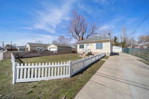 Bungalow featuring a fenced front yard, a garage, an outdoor structure, and a front yard