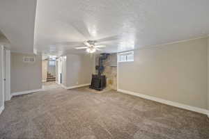 Unfurnished living room featuring visible vents, stairway, carpet flooring, baseboards, and a wood stove