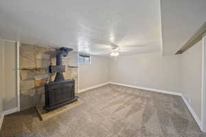 Unfurnished living room with visible vents, baseboards, carpet, a wood stove, and a textured ceiling