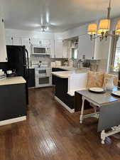 Kitchen featuring white appliances, light countertops, a peninsula, backsplash, and dark wood-type flooring
