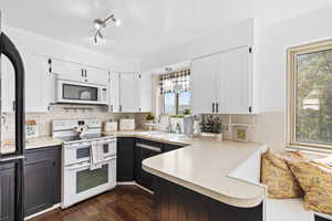 Kitchen featuring white cabinetry, white appliances, light countertops, and backsplash