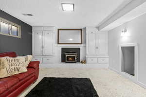 Living room with a textured ceiling, speckled floor, and a brick fireplace